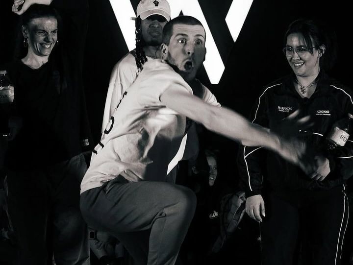 Slim B is in the center of the picture. There are three people behind him and looking at him.