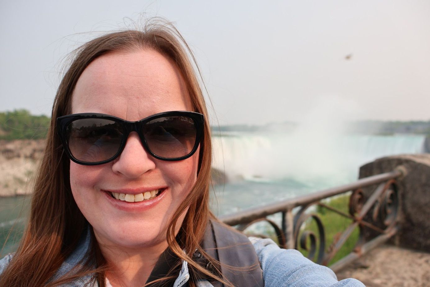 Jacqueline is posing for a photo overlooking Niagara Falls, Canada