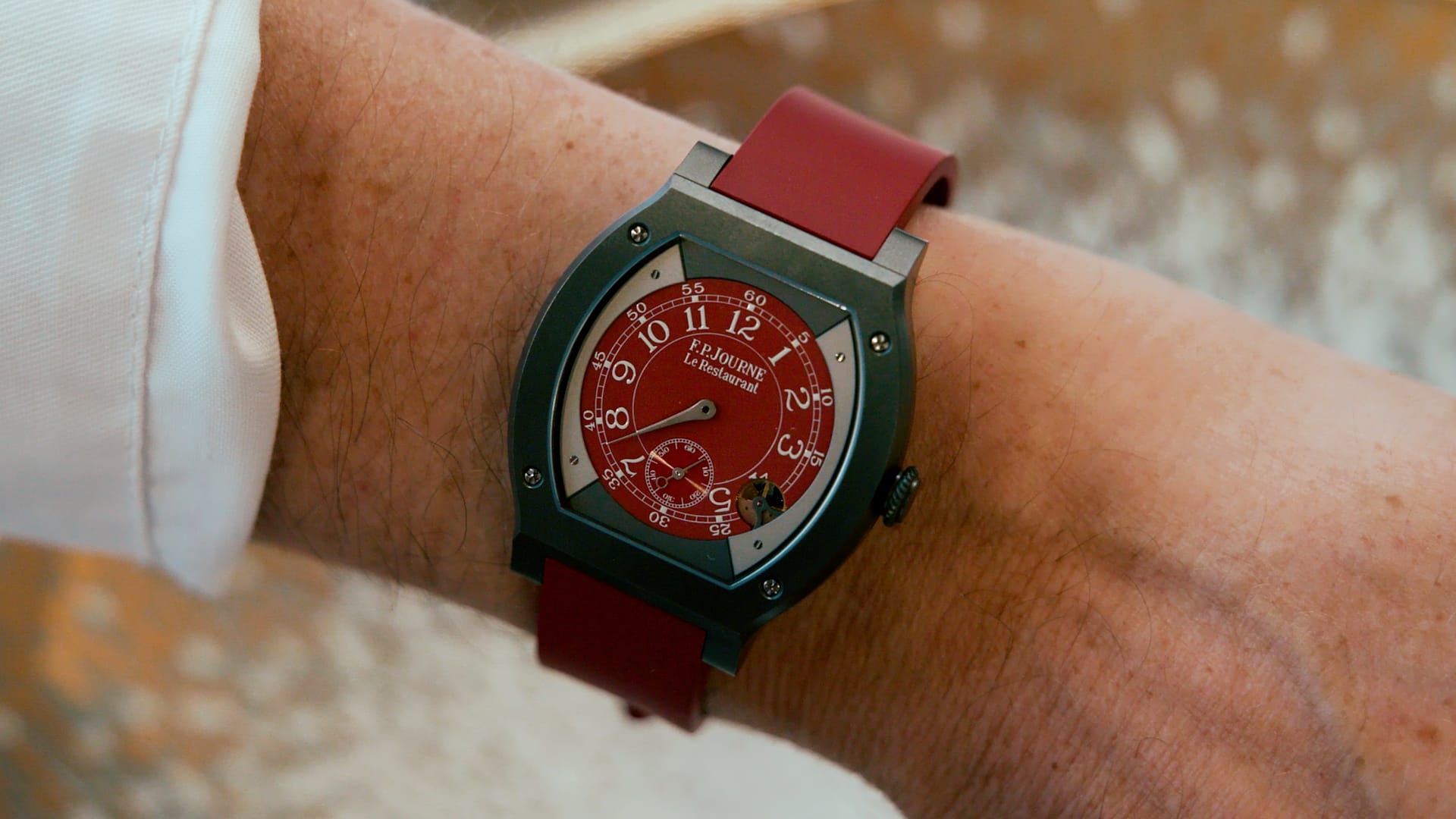 Close-up of a wrist wearing a red F.P. Journe watch with green strap, photographed during the restaurant preview event.