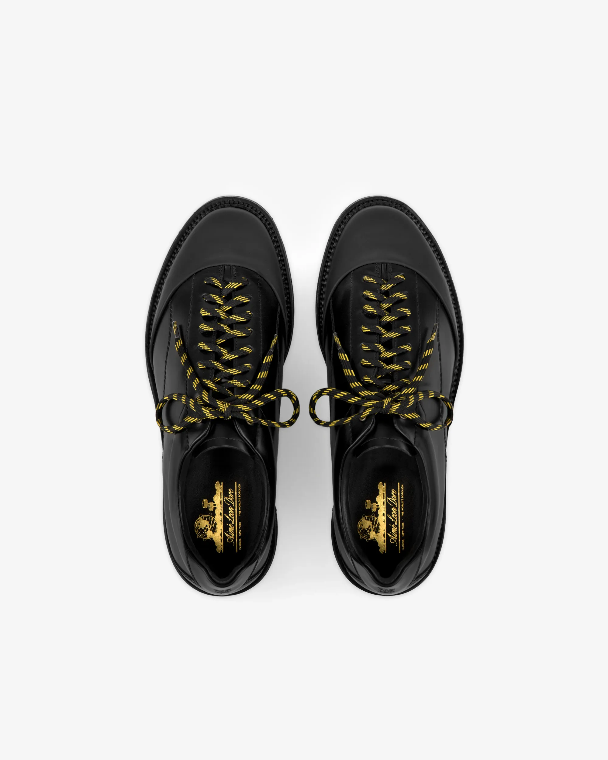 Pair of black leather designer loafers with gold logo detail and braided laces, photographed on a white background.