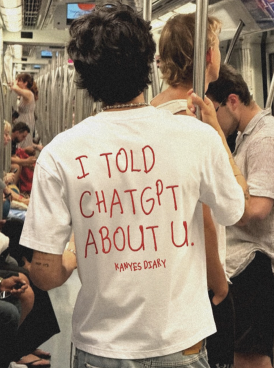 Person wearing a white T-shirt with red handwritten text “I TOLD CHATGPT ABOUT U,” standing in a metro.