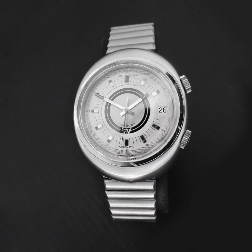 Vintage Jaeger-LeCoultre Memovox automatic wristwatch with silver dial, concentric design, and date display, photographed on a dark background.
