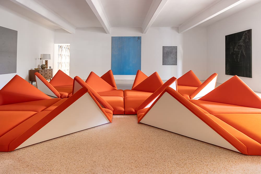 Installation view of Pierre Paulin’s Mushroom Chairs arranged in a geometric pattern inside a white-walled gallery with orange flooring.