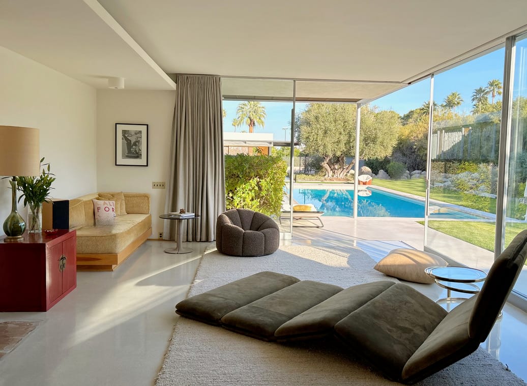 Contemporary home interior with minimalist Pierre Paulin pieces, sunlight streaming across a beige carpet.