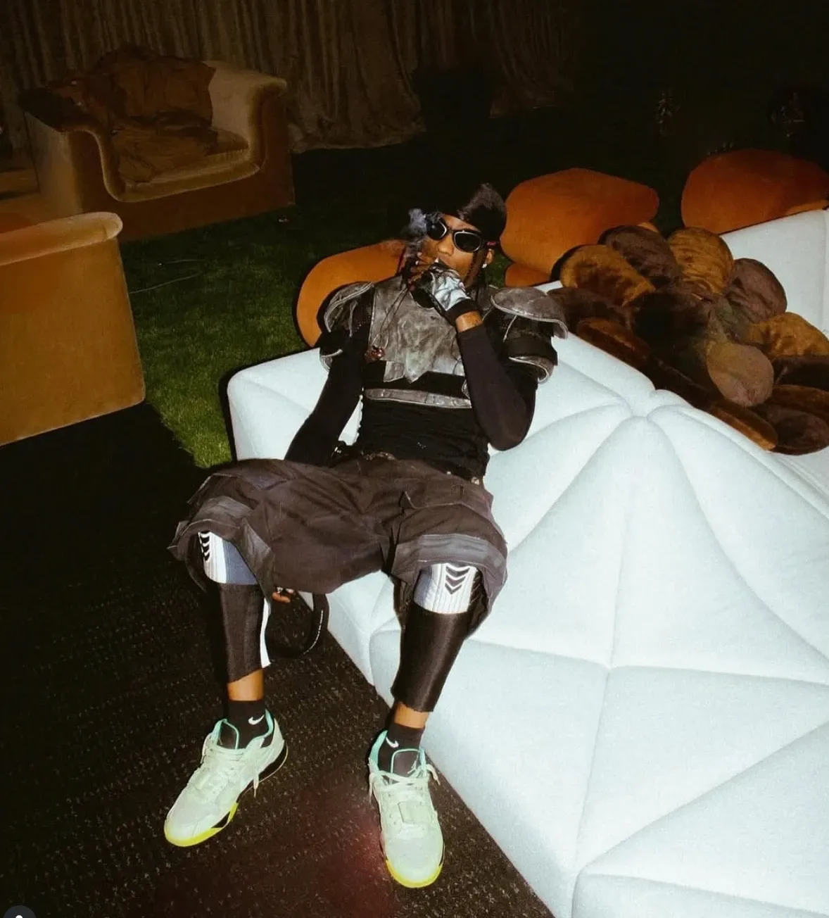 Person reclining on a cream-colored Pierre Paulin chair in a dimly lit room, surrounded by warm orange walls.