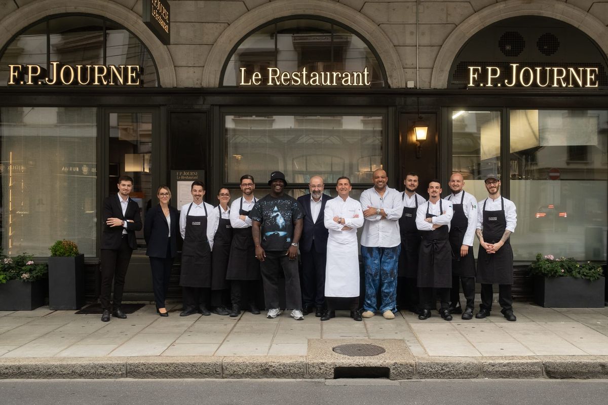 Group photo in front of F.P. Journe Le Restaurant, the team standing in front of the restaurant entrance in Geneva, beneath the gold-lettered signage.