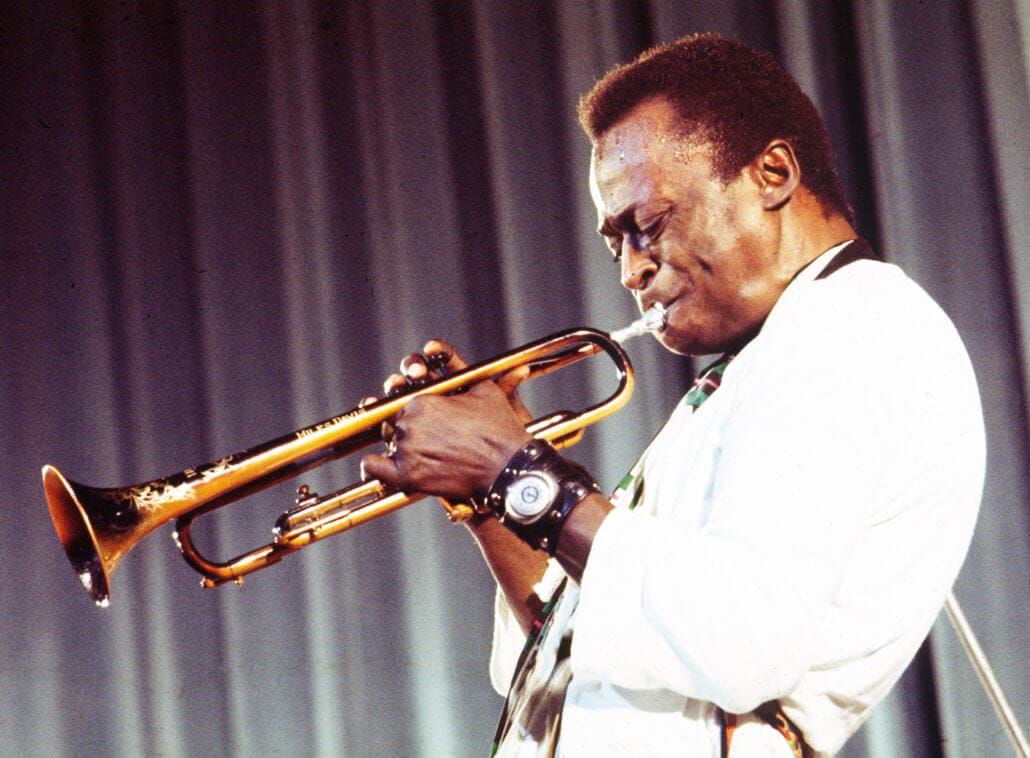 Miles Davis musician playing trumpet on stage wearing a Breitling Navitimer watch, captured mid-performance — a timeless connection between jazz, rhythm, and horology.