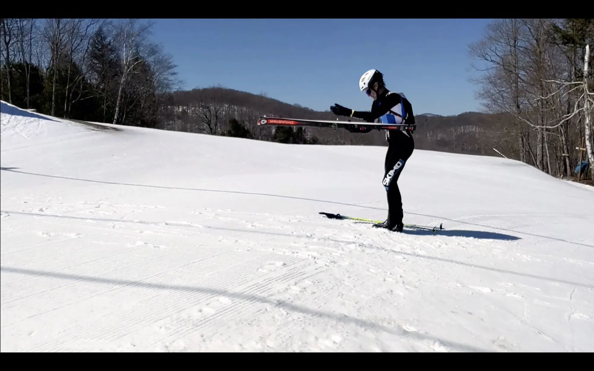 A photo of a skimo racer entering a boot-to-skin transition, removing skis from their holster