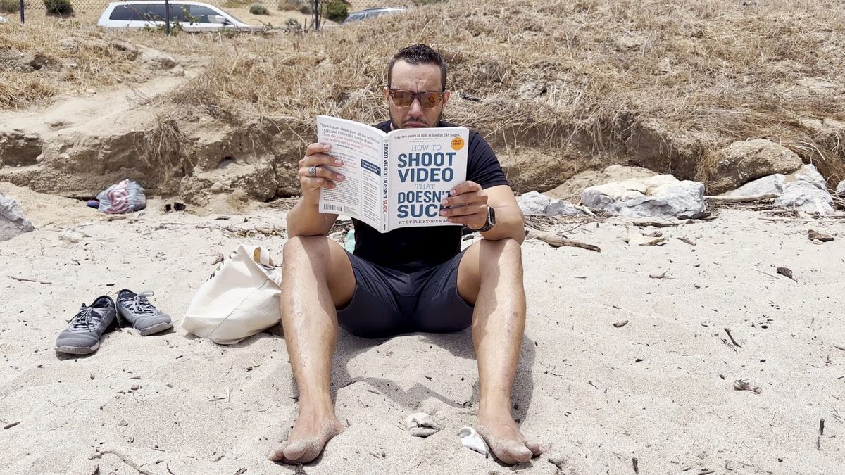 a man reading a book on the beach