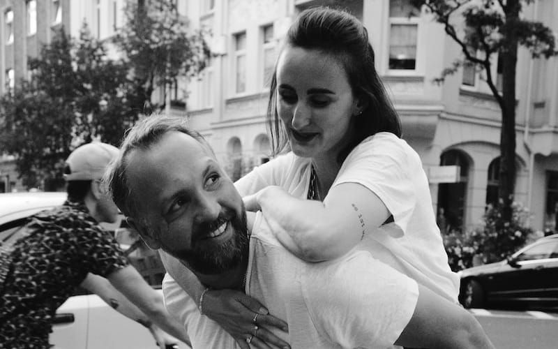 man in white shirt and black denim jeans holding girl in black and white photography