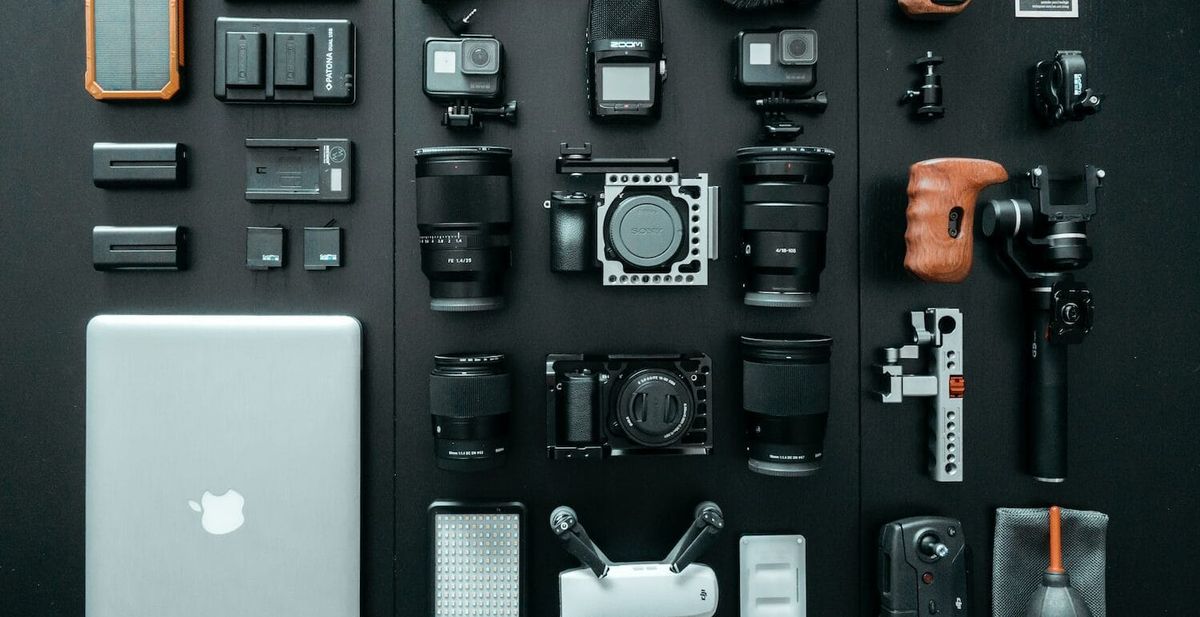 Digital equipment, including a laptop and camera, laid out on a black surface.