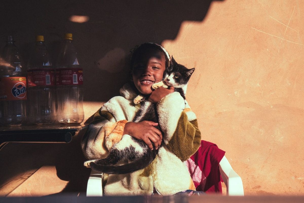 A child with her kitten against a brown wall
