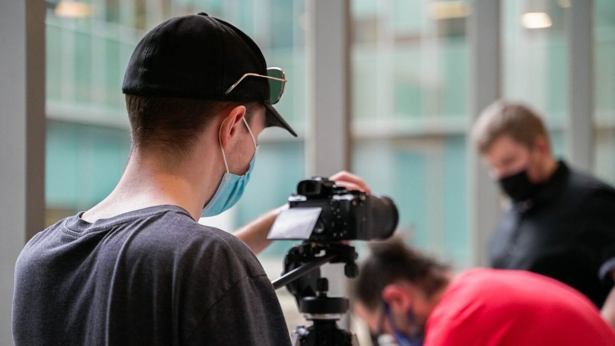 An individual with a mask holding a camera and recording