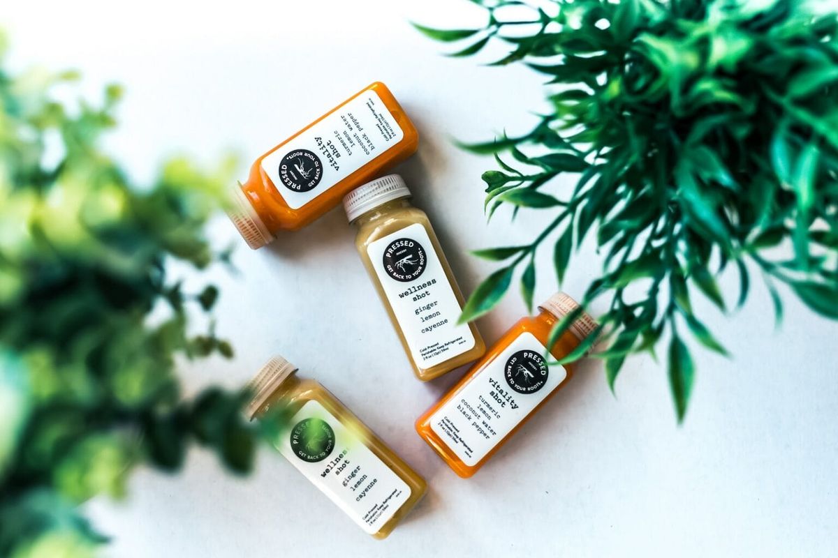 Several wellness bottles laid against a white background with grass accenting