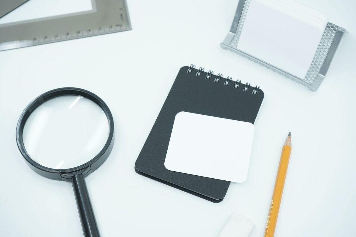 A table with a pencil, pad, and magnifying glass laid out.