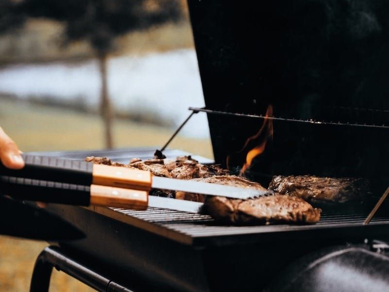 person grilling meat outdoors