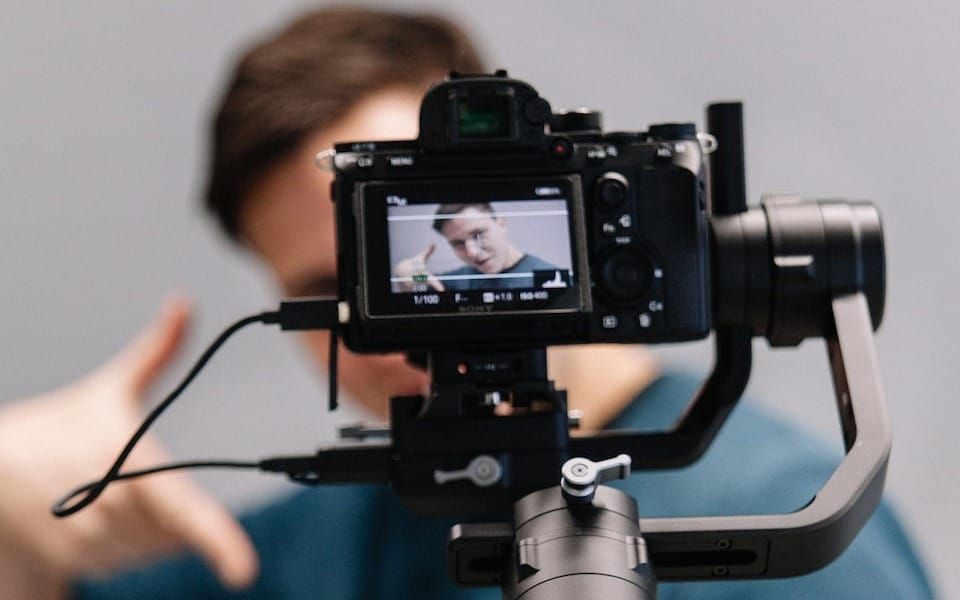 man holding black DSLR camera with stabilizer