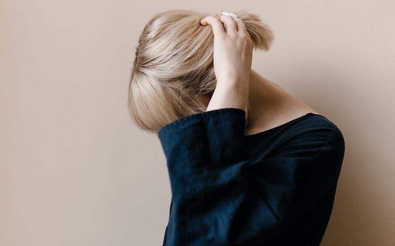 woman in blue shirt covering her face with her hair