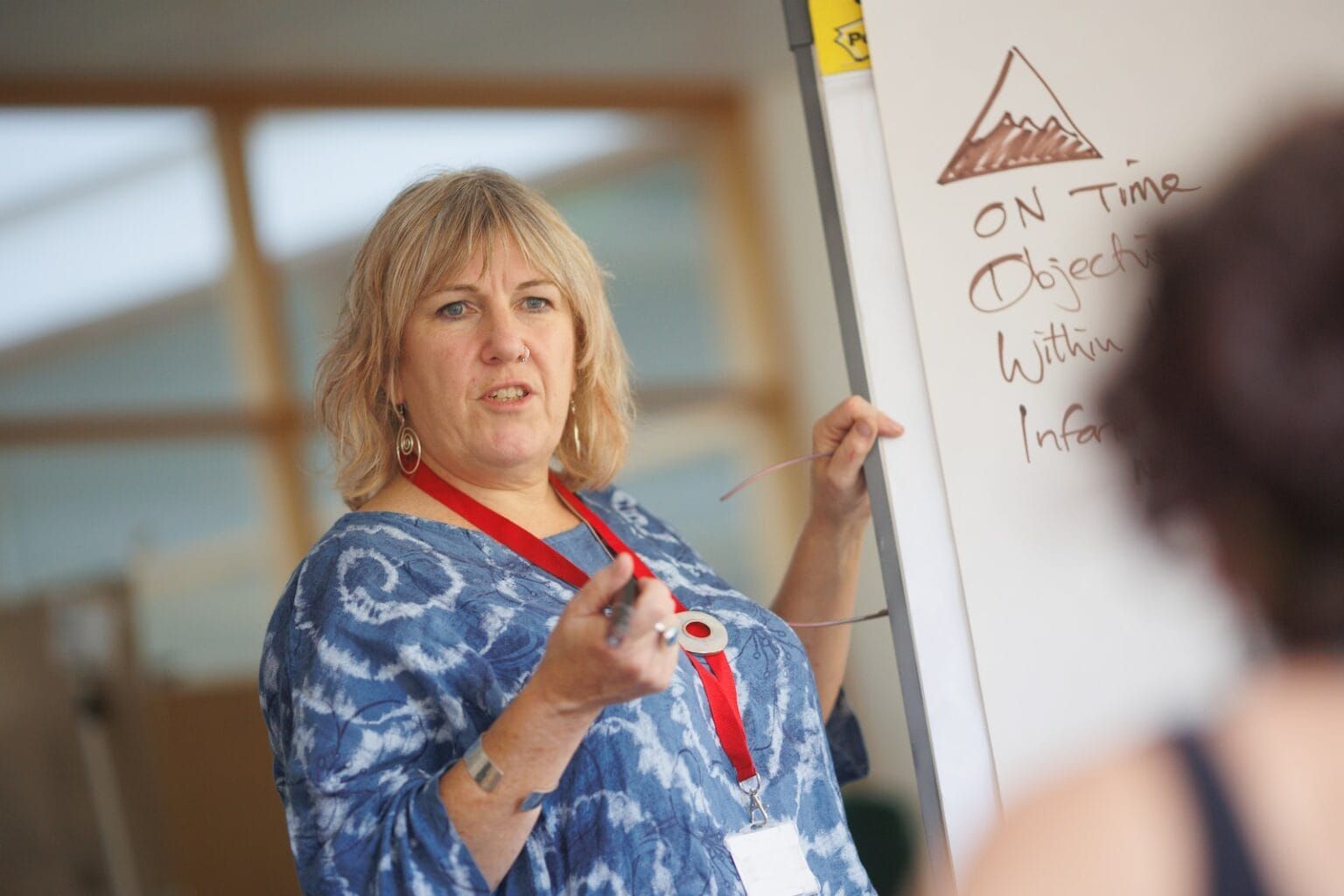 A woman leading a discussion next to a whiteboard