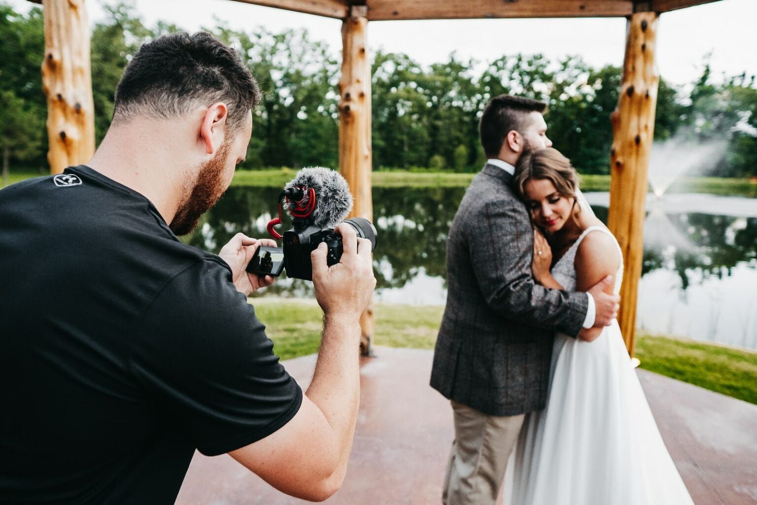 A man wearing a black shirt taking wedding photos of a couple
