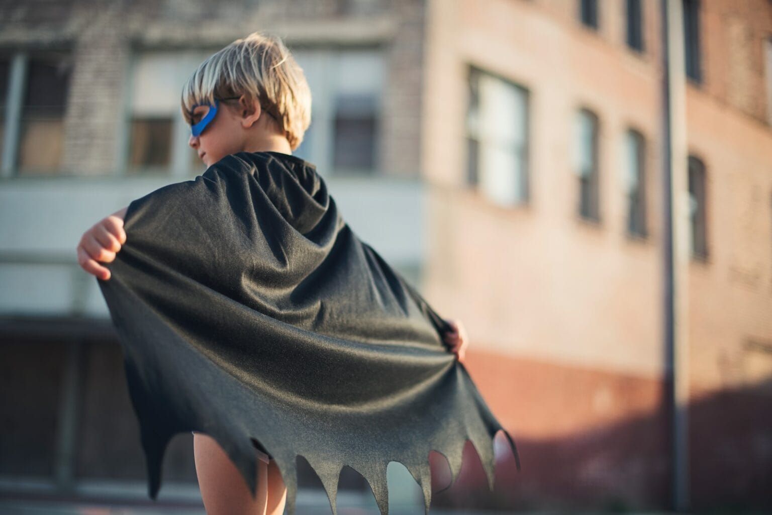 A child wearing a hero cape and mask