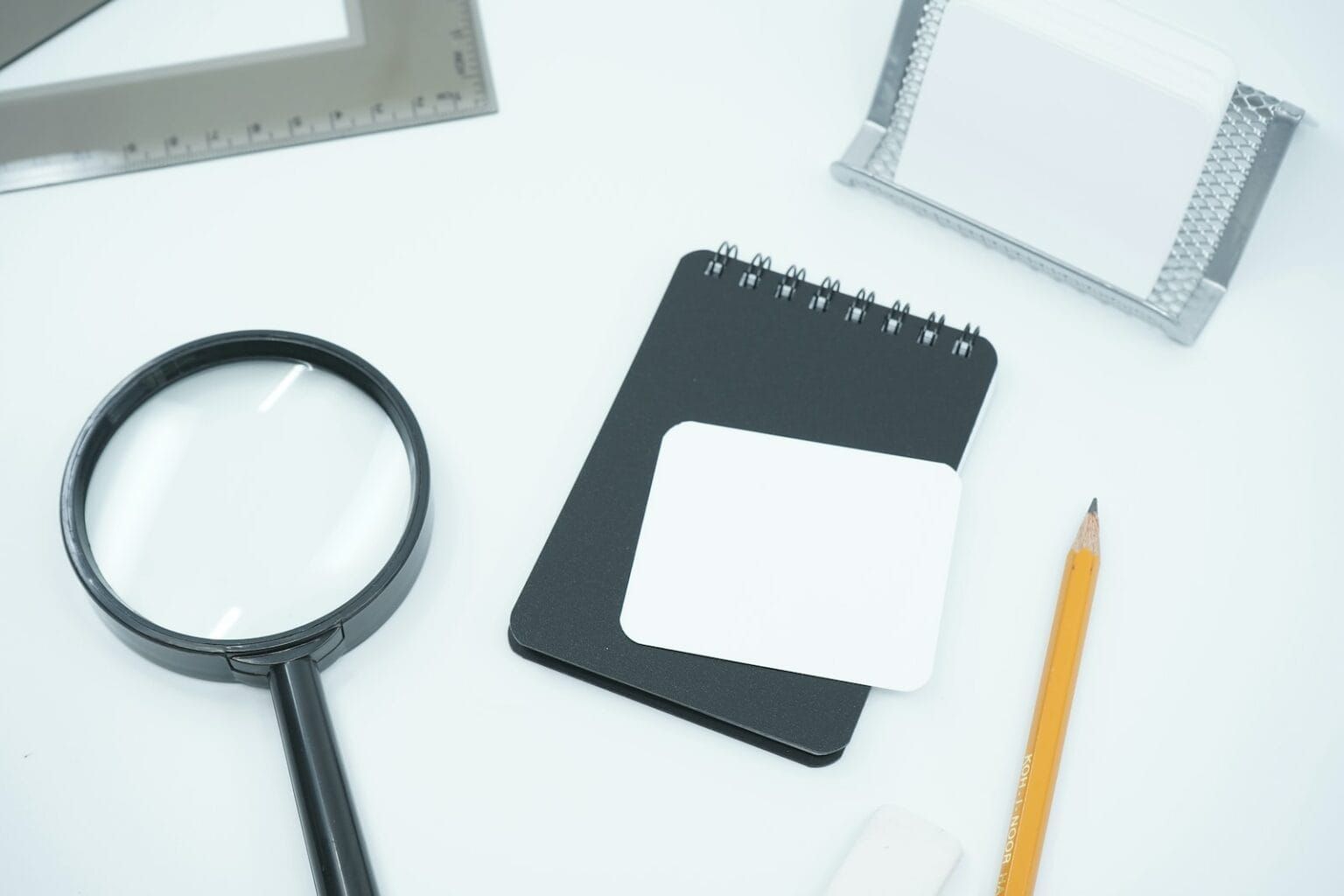 A table with a pencil, pad, and magnifying glass laid out.