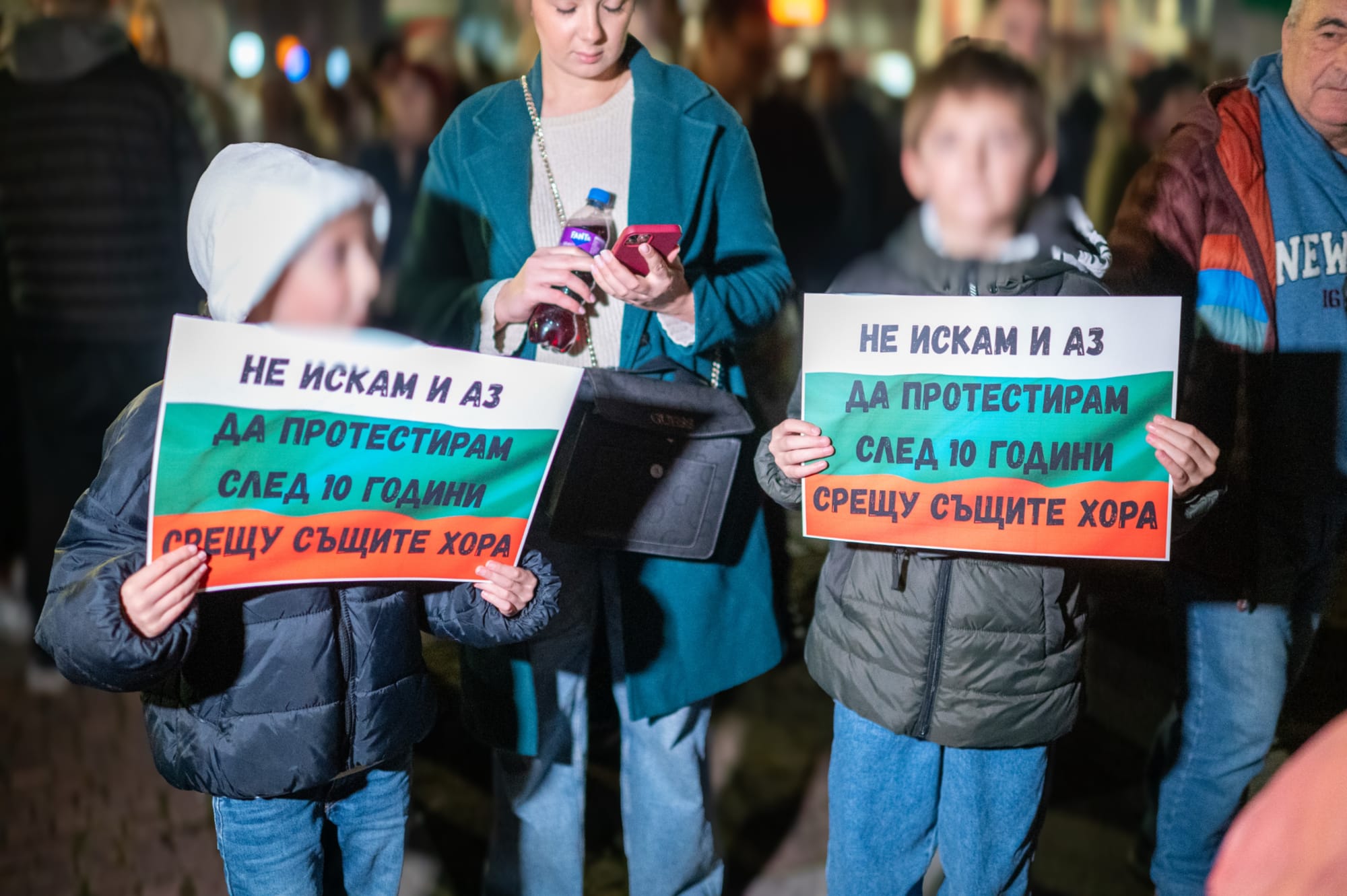 На снимката две деца държат плакат, който гласи, че не искат и те да протестират след 10 години срещу същите хора. Лицата им са замъглени.