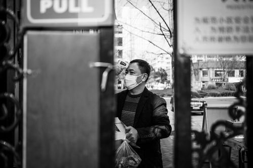 Първите дни на епидемията: мерене на температурата на китайски гражданин с маска