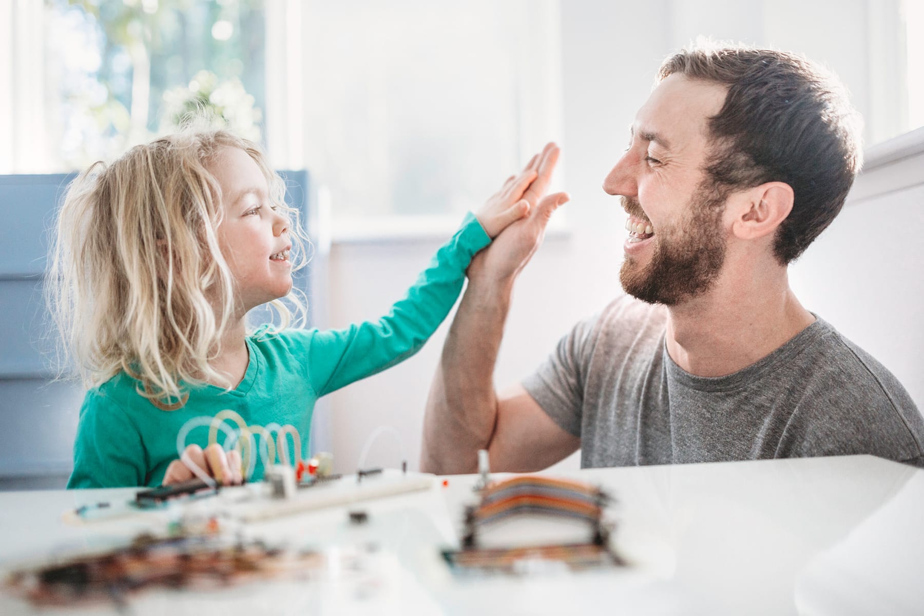 Child high fives their father after completing an electronic kit