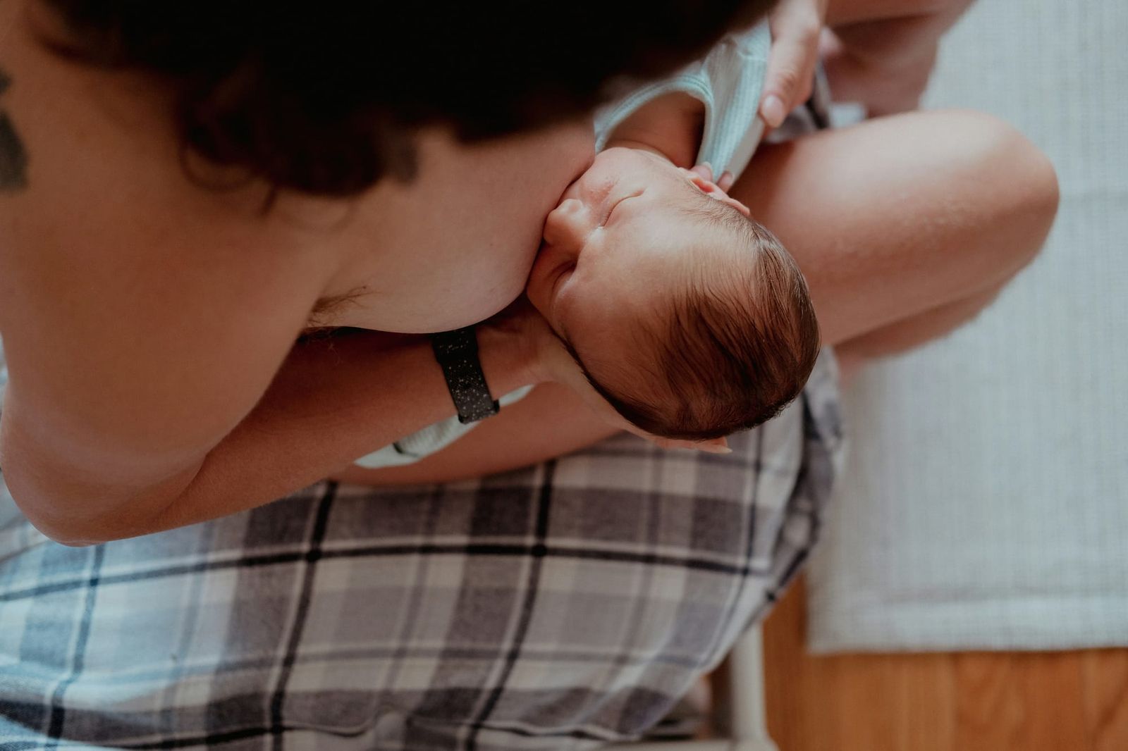 Photograph of a mother breastfeeding her tiny baby, shown from above