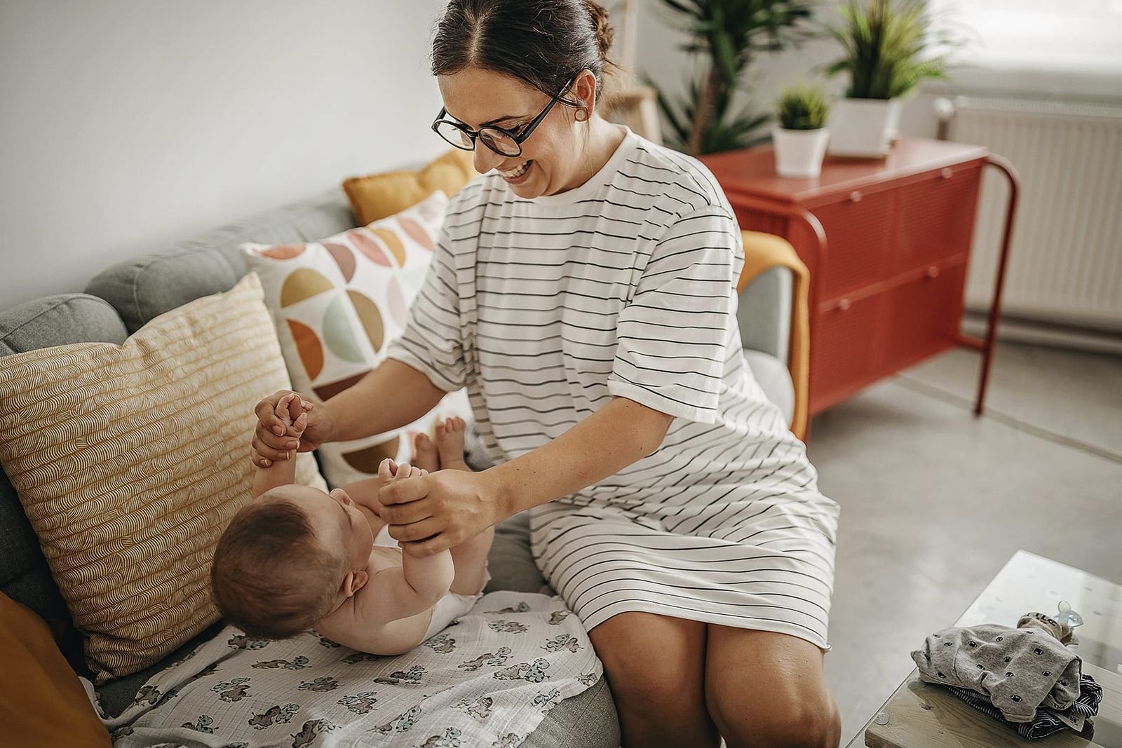 Photograph of a mother with her baby on a sofa, during a nappy change