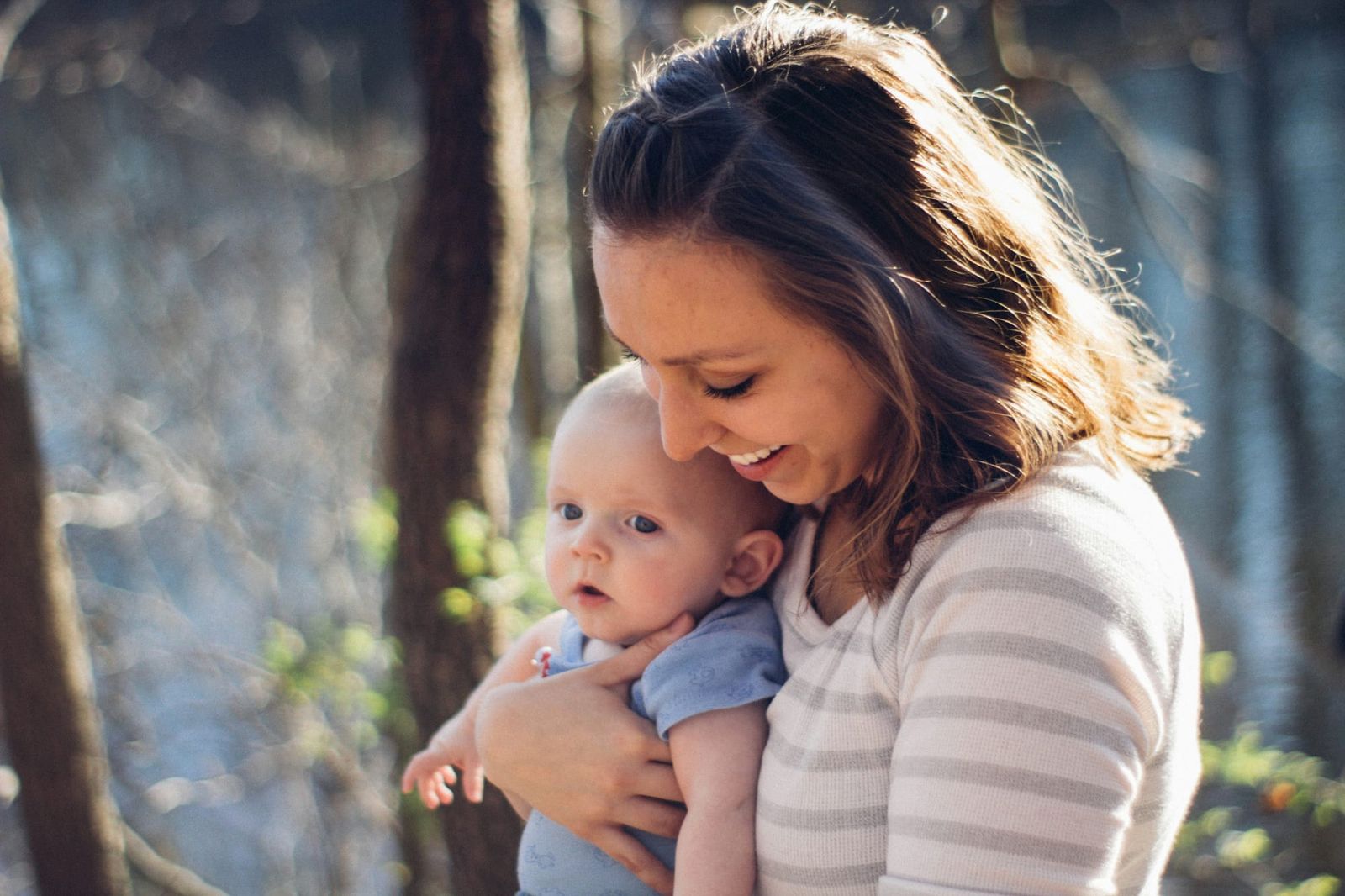 Photo of a happy mother holding her baby against her chest, facing out