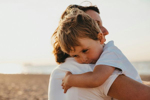 Photograph of a mother holding her son, his arm around her shoulder and his head resting against her
