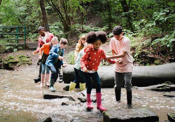 Teenager helping friend across river