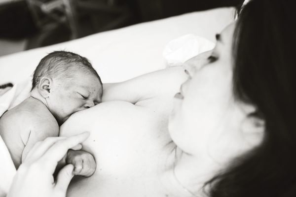 New mother holds a tiny newborn infant against her chest