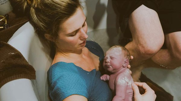 New mother in a birthing pool with her brand new baby, still covered in vernix