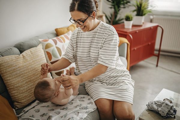 Photograph of a mother with her baby on a sofa, during a nappy change