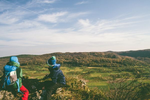 Photograph of two young people out hiking with stuffed backpacks and hills in the distance