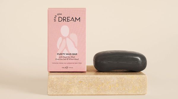 Dead Sea Dream Purity Mud Bar with its pink box on a stone block