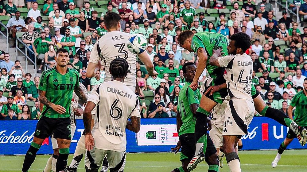Guilherme Biro heading a ball through a crowd of Austi FC and New York Red Bulls players to score a goal