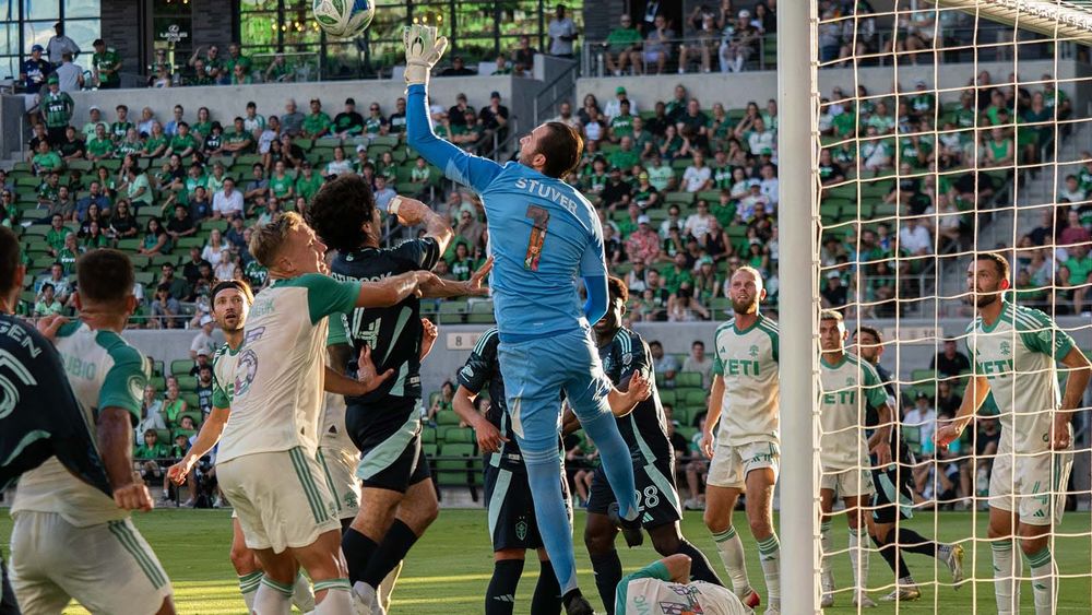 Brad Stuver getting ready to bat a ball away, surrounded by Austin and Seattle players