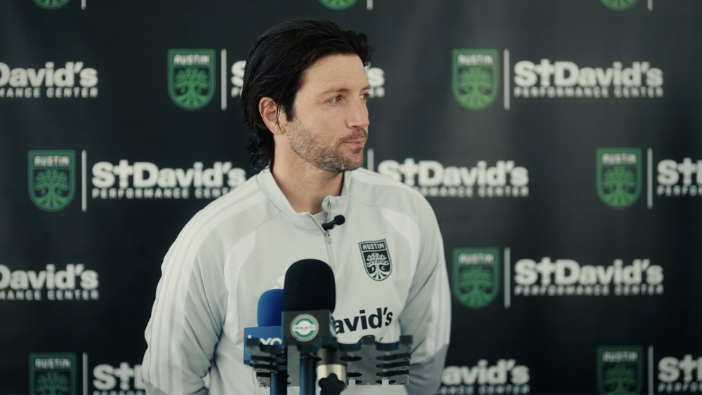 Ilie Sánchez at media availability with microphones in front of him