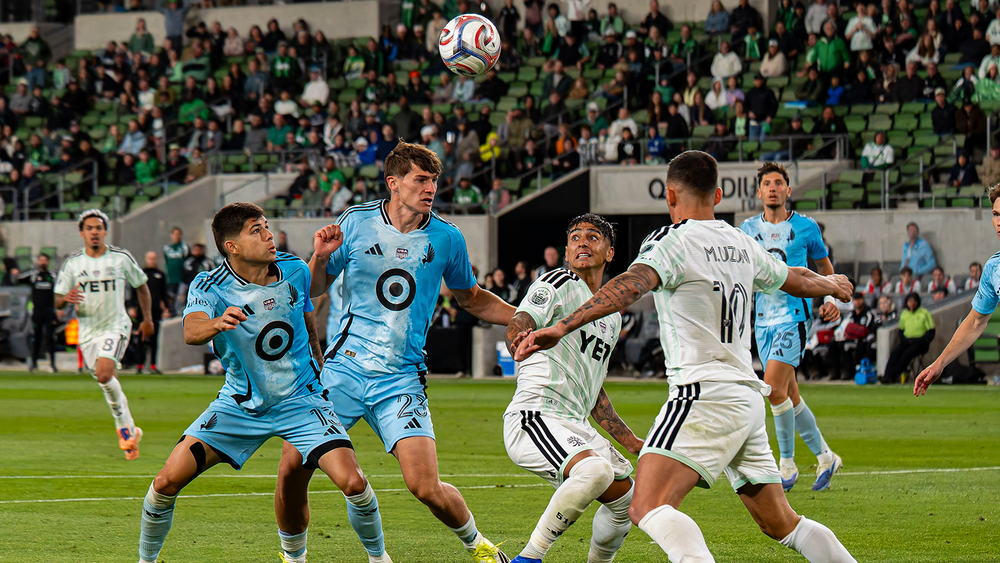 Austin FC and Minnesota United FC players battling to control a soccer ball in mid-air