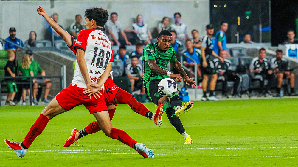 Joseph Rosales kicking ball past two Tijuana players