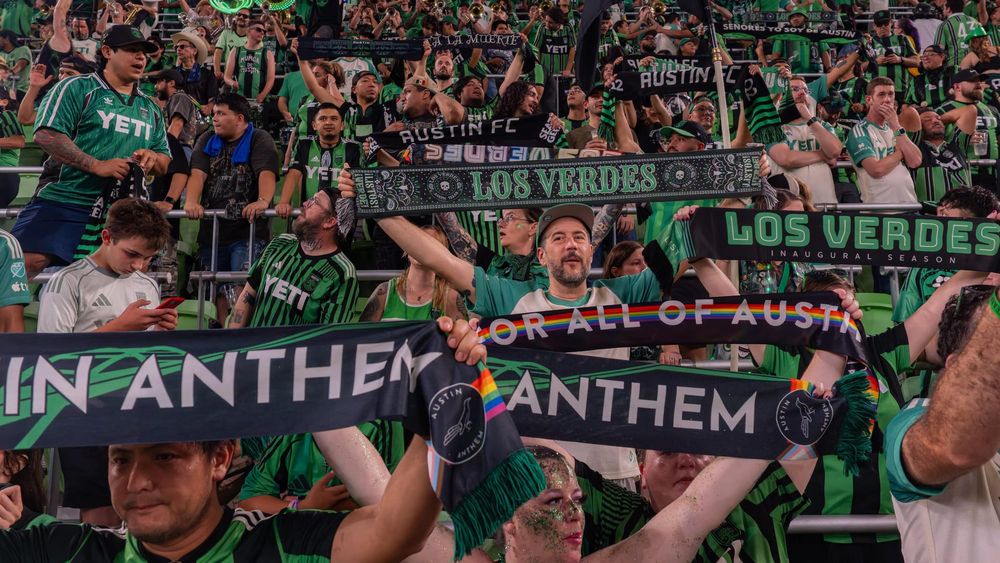 Austin FC supporters holding scarves repping Austin Anthem and Los Verdes