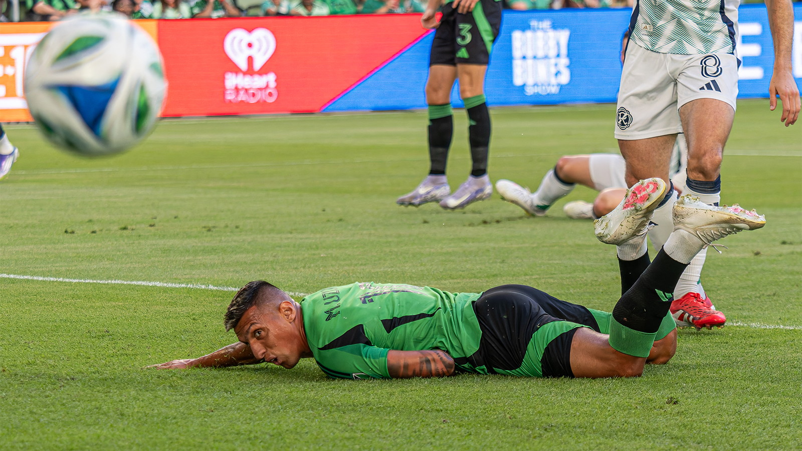 Myrto Uzuni lying on field watching ball move past him