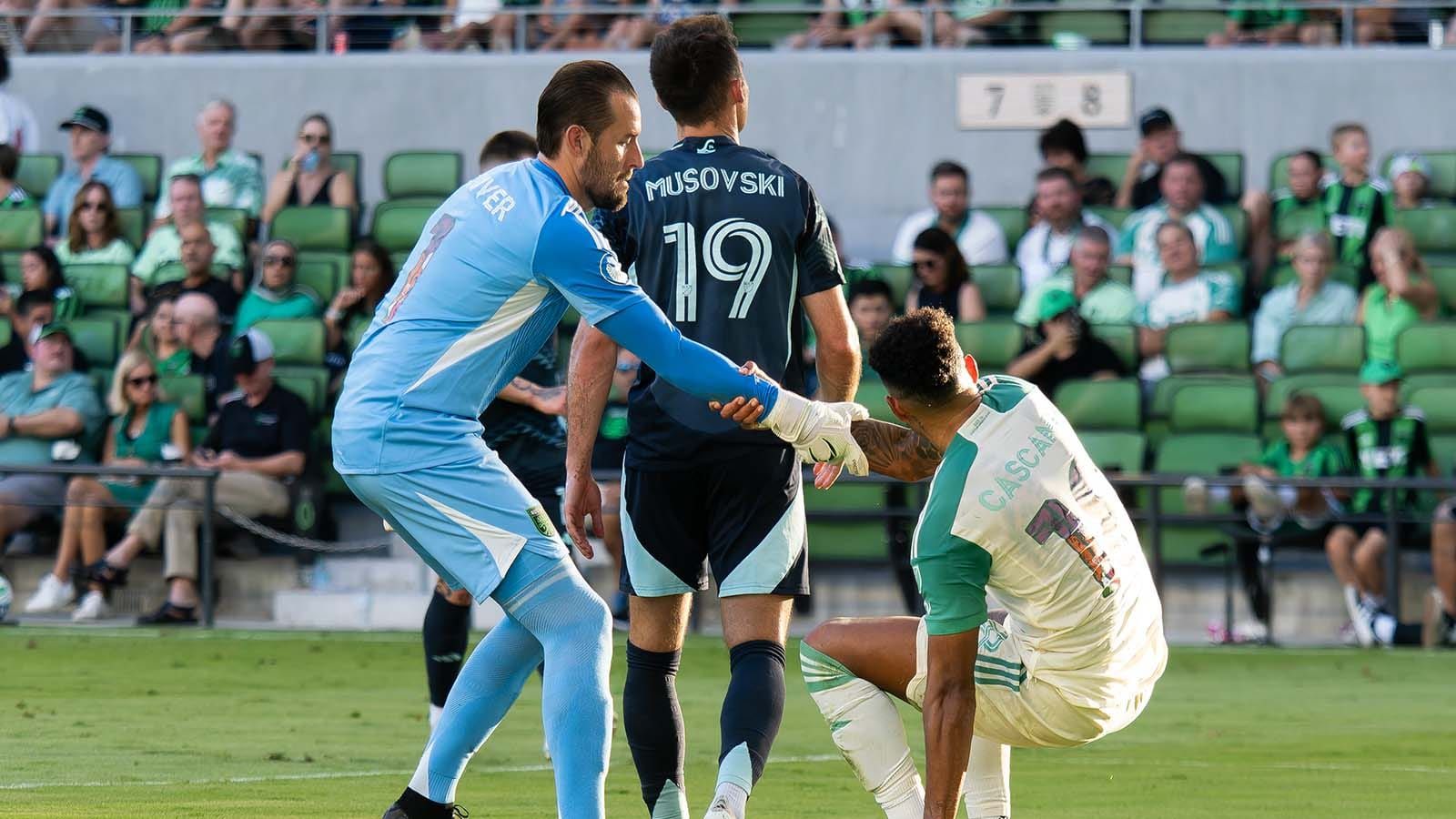 Brad Stuver helping Julio Cascante up in Austin FC match against Seattle Sounders FC