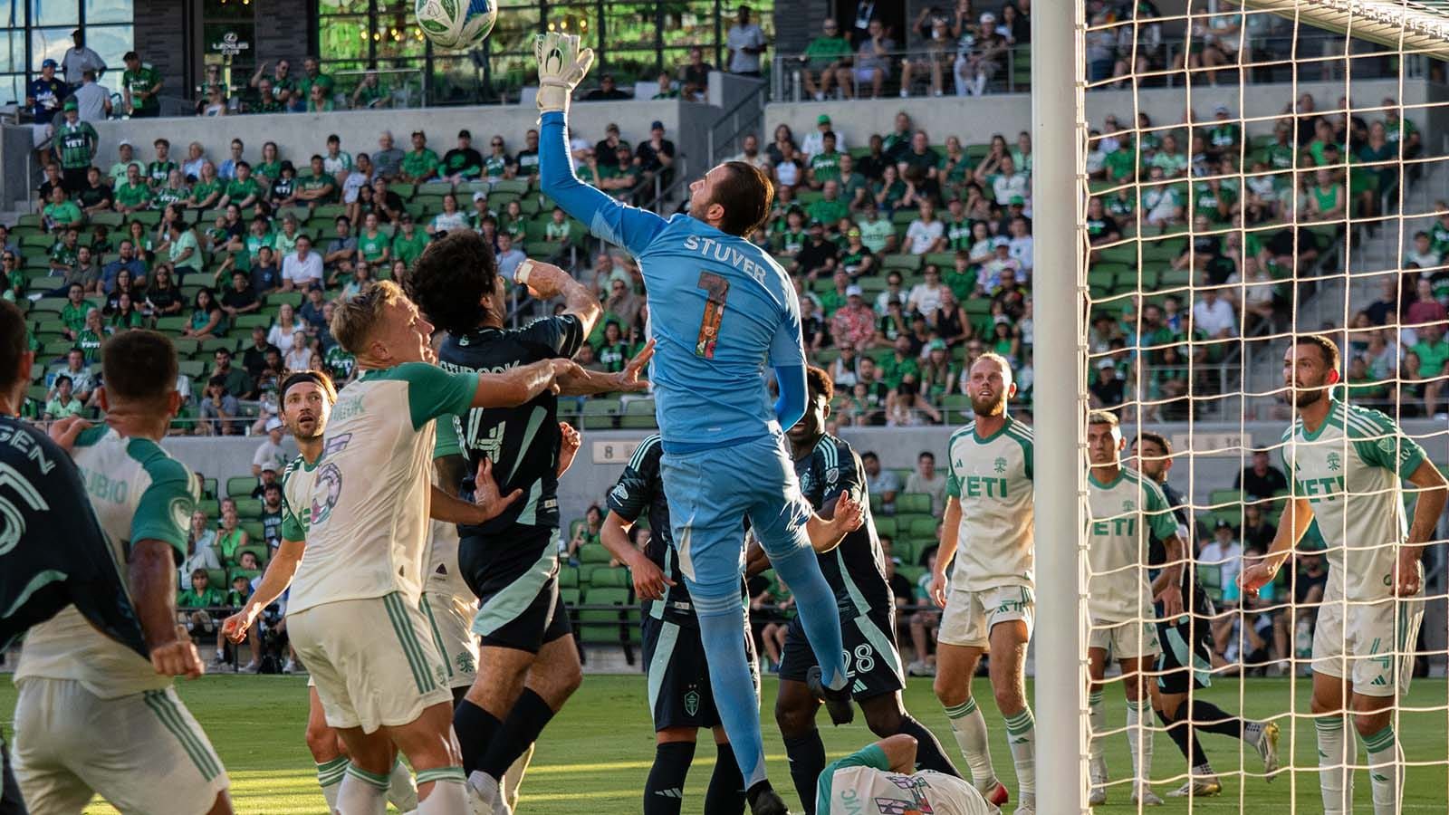 Brad Stuver getting ready to bat a ball away, surrounded by Austin and Seattle players