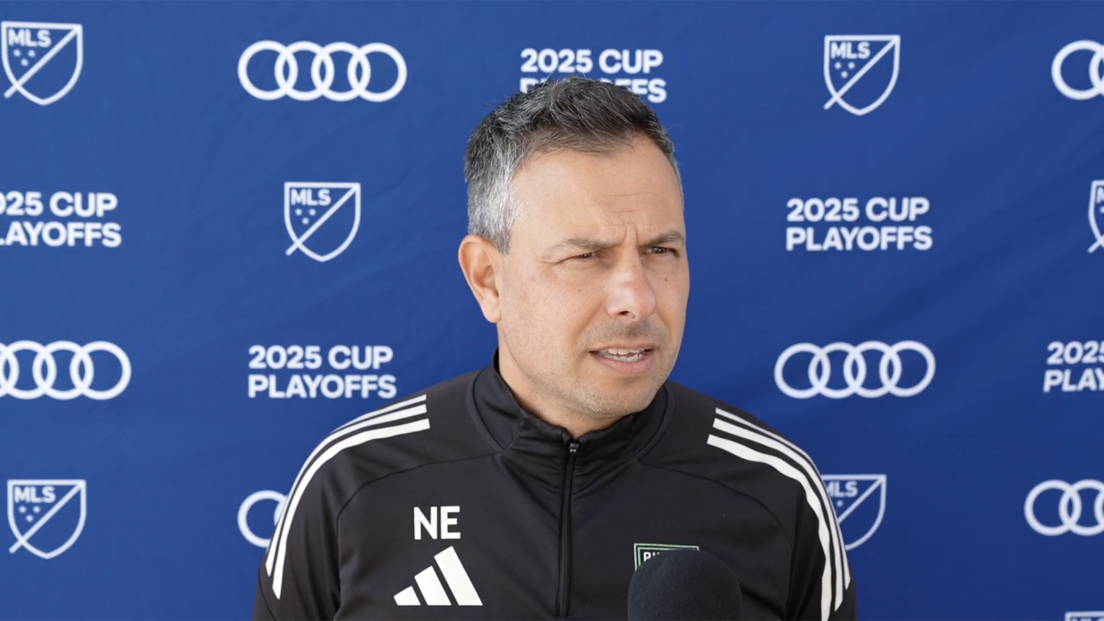Nico Estévez speaking to media in front of an MLS playoffs backdrop