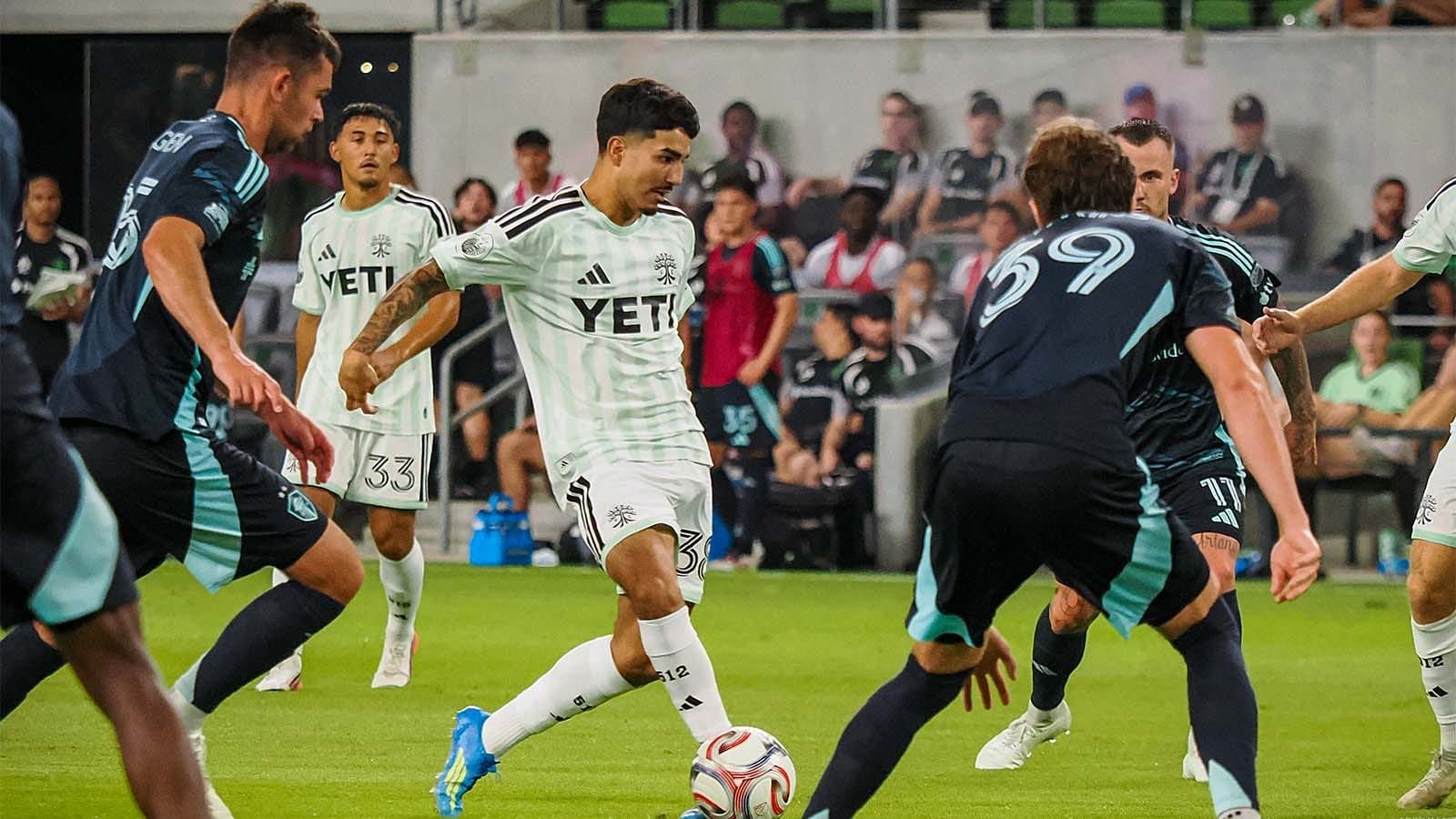 Austin FC's Ervin Torres, surrounded by Seattle Sounders players, about to pass the ball